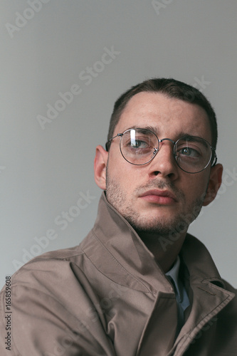 Fototapeta Naklejka Na Ścianę i Meble -  A lonely handsome guy in a raincoat and glasses with different moods