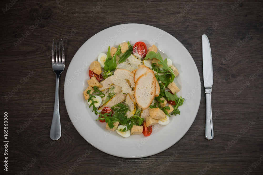 Caesar salad in a white plate on a wooden background