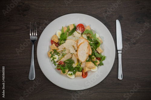 Caesar salad in a white plate on a wooden background