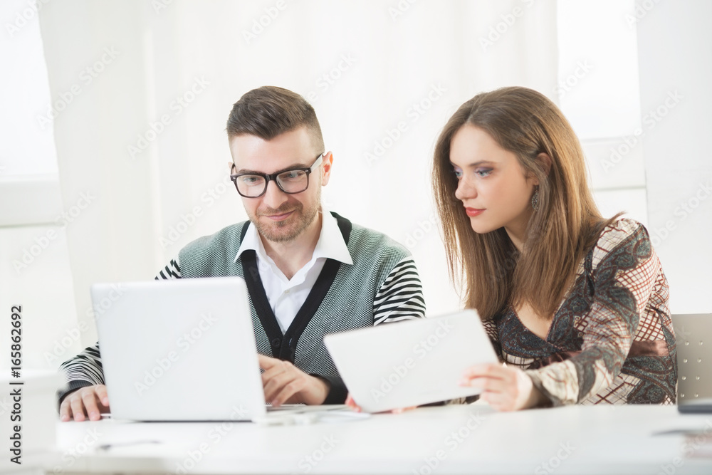 Young coworkers in the office looking in to a laptop screen Young coworkers in the office looking in to a laptop screen