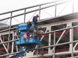 construction worker at construction site using lifting boom machinery