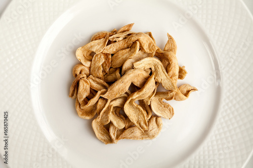 Small pile of raw soy meat slices on a plate top view. Some soybean meat uncooked slices on a white background