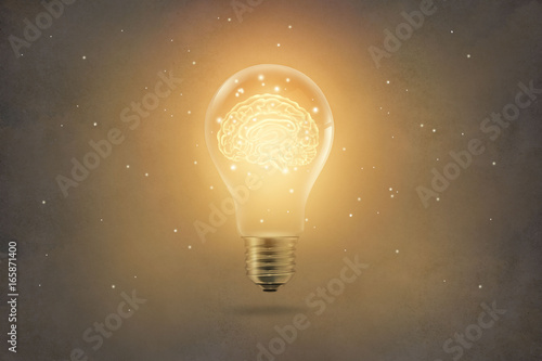 golden brain glowing inside light bulb on paper texture background photo