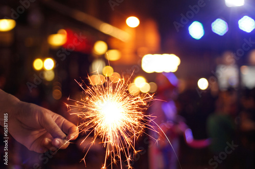 hand holding sparkler or firework on street night background