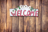 Old metal sign in front of a white wooden wall - Welcome