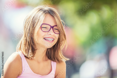Szczęśliwa uśmiechnięta dziewczyna z stomatologicznymi brasami i szkłami. Młoda śliczna caucasian blond dziewczyna jest ubranym zębów szelki i szkła