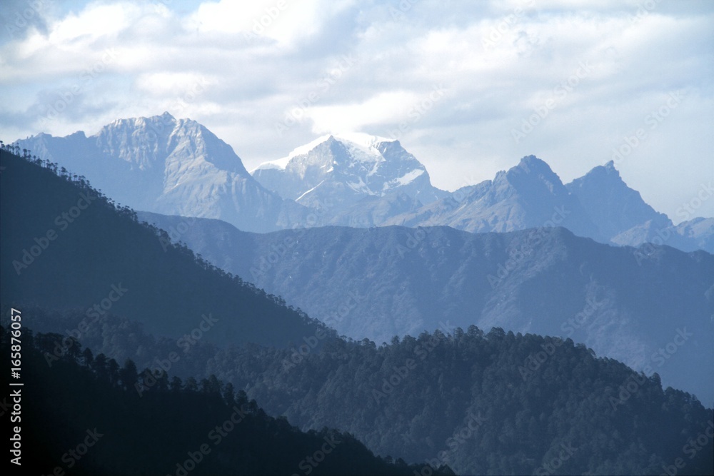 Morning mountain landscape with layer of mountain peaks covered with coniferous deciduous forests. View from Dochula Pass on the road from Thimphu to Punaka, Bhutan