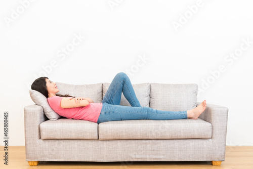 smiling woman lying on the couch sofa day dreaming photo