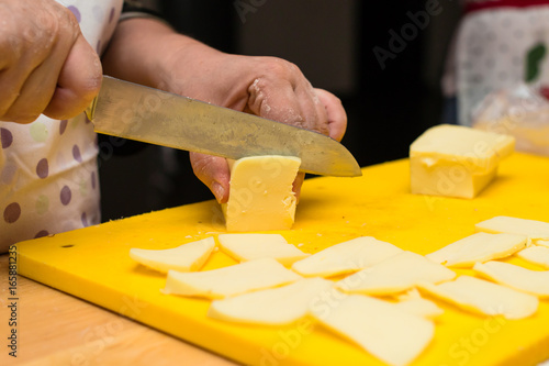 woman hands slices cheese to make an Italian pizza, process of preparing pizza. Cooking time, cooking concept, selective focus