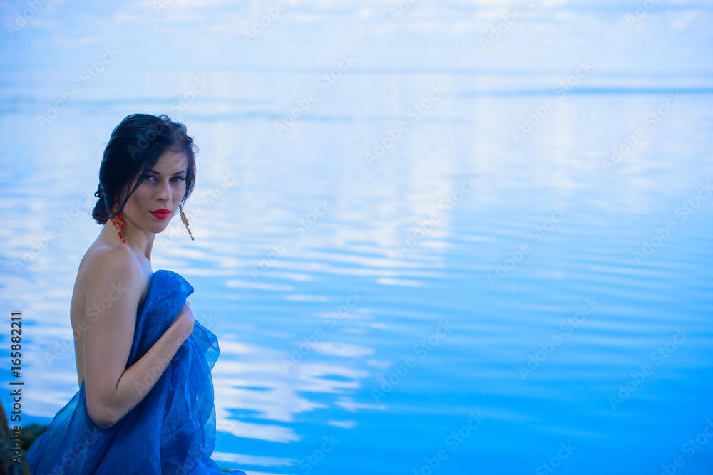 A beautiful stylish young woman with thin figure in cloth rest and relaxes on the beach in the morning, in blue water A beautiful stylish young woman with thin figure in cloth rest and relaxes on the beach in the morning, in blue water