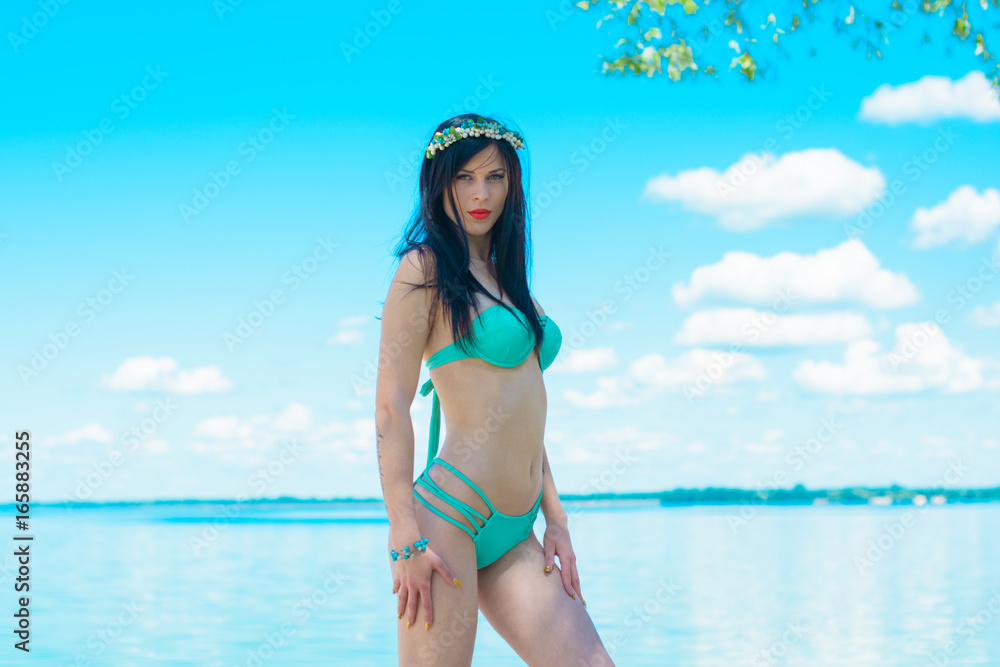 A beautiful stylish young woman with thin figure rest and relaxes on the beach in the morning, near beach and blue water A beautiful stylish young woman with thin figure rest and relaxes on the beach in the morning, near beach and blue water