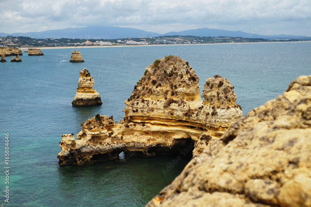 rocks cliffs in Atlantic ocean near Camilo beach (Praia do Camilo) and colorful blue sky, Lagos, Algarve, Portugal 