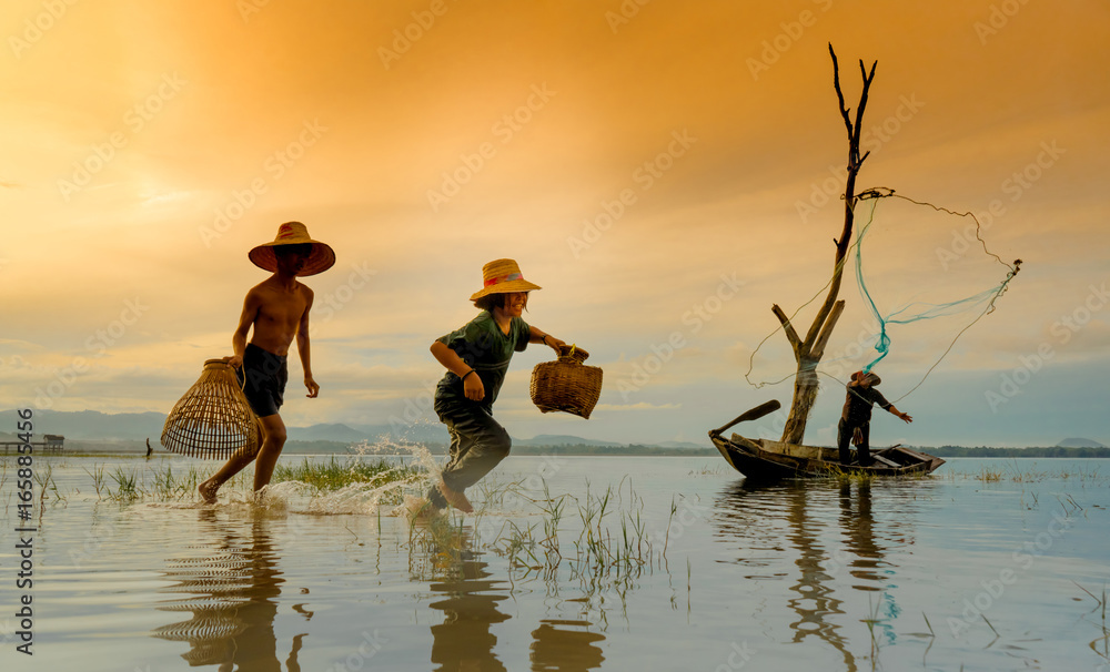 Children boy and girl run catching fish, Fisherman fishing nets on boat at  lake, river sunset thailand Stock Photo
