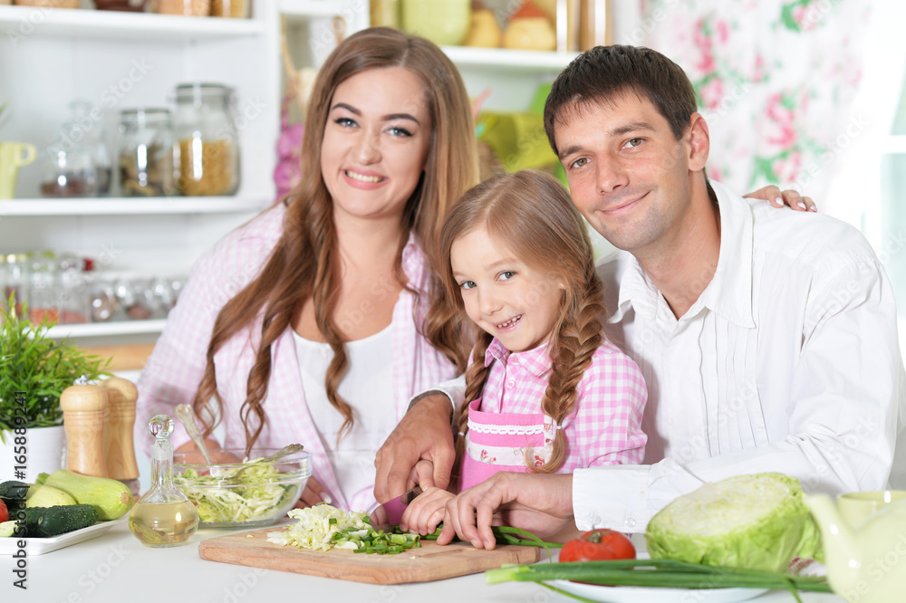 parents with daughter preparing dinner 