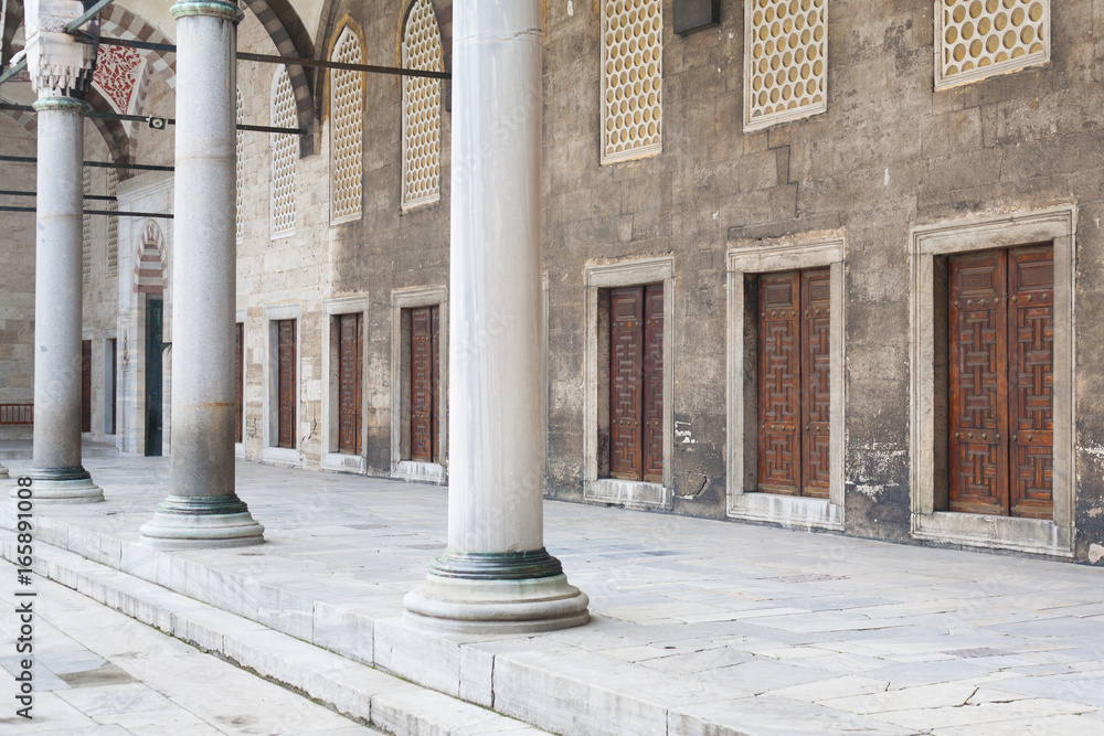 Portico with marble columns and doors in a row in the courtyard of an ancient mosque