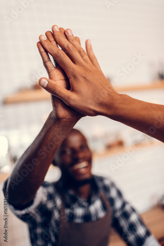 Canvas-taulu african american barista giving highfive to client in coffee shop
