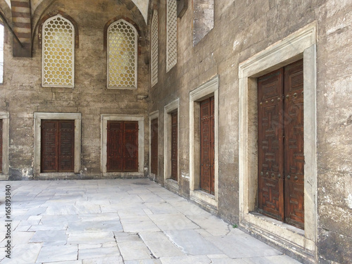 Portico with doors in a row and grids in the courtyard of an ancient mosque © Andrea Lolli Web
