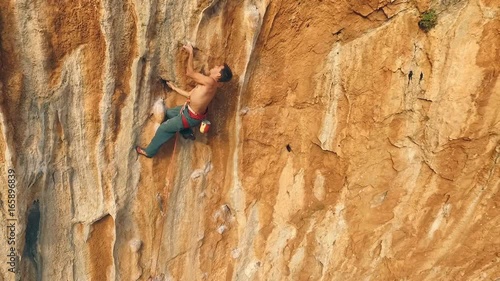 Climber climbs on rock bottom using insurance