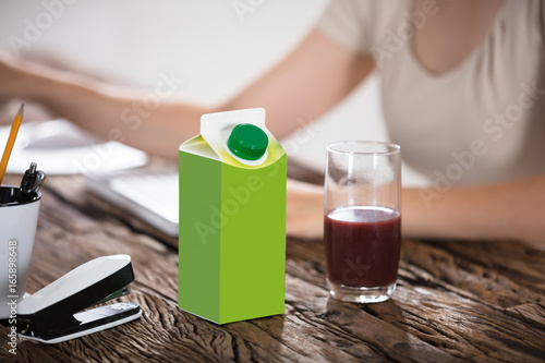 Carton And Glass Of Juice On Desk
