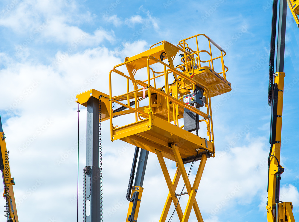 custom made wallpaper toronto digitalHydraulic lift platform with bucket of yellow construction vehicle, heavy industry, blue sky and white clouds on background