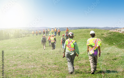 Group of workers in hardhats walking and inspecting grass field