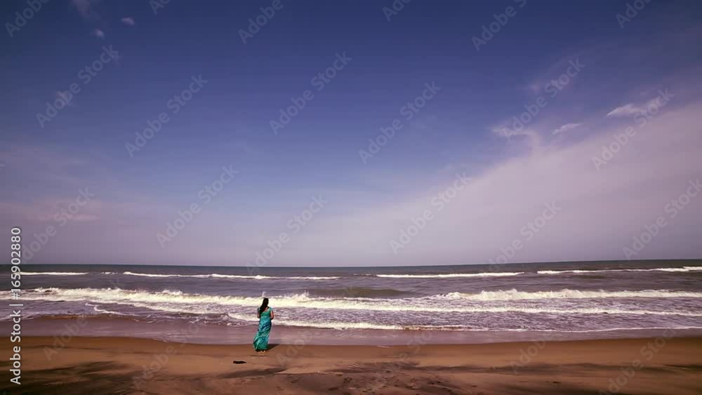 Young woman standing on beach and enjoying view Young woman standing on beach and enjoying view