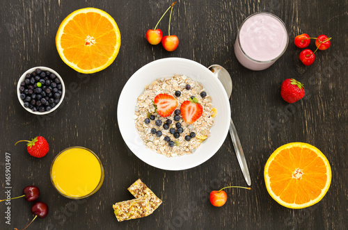 Healthy breakfast of muesli, berries with yogurt and orange juice on dark background.