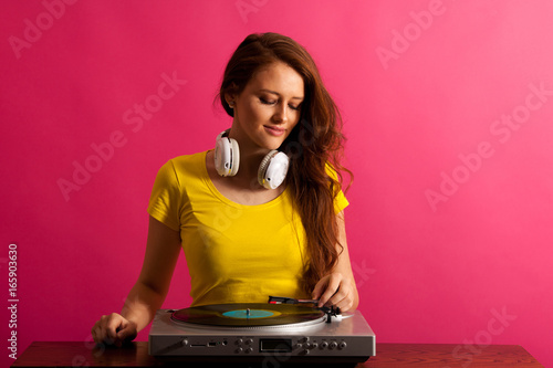 Woman DJ playing on gramophone over pink background