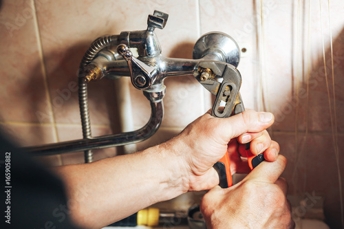 Man repair and fixing leaky old faucet in bathroom photo