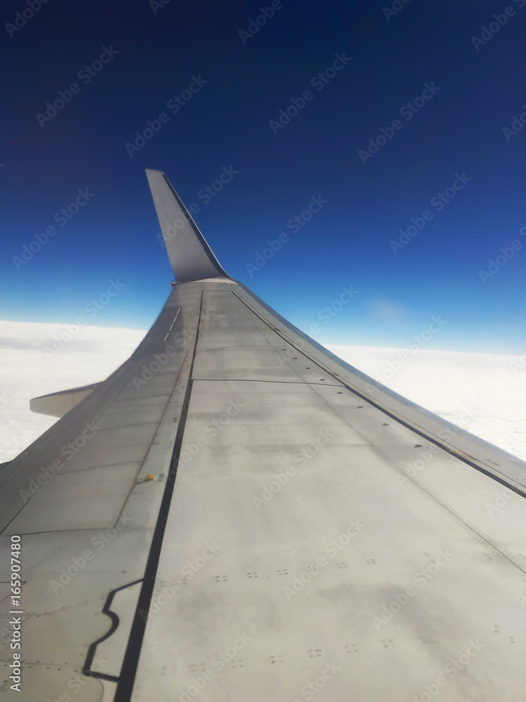 Airplane wing and blue sky on background