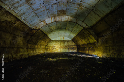 Inside big rusty underground abandoned fuel tank for refueling diesel submarines at repair factory 