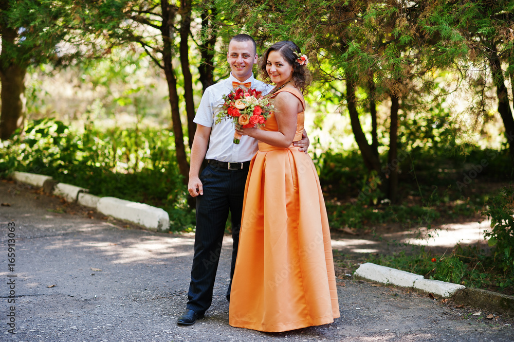 Gorgeous bridesmaid posing with groomsman in the park on the wedding day.