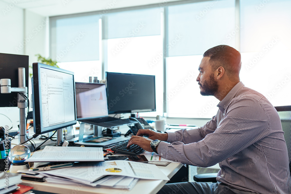 © Jacob Lund - Businessman working on computer at his desk in office.