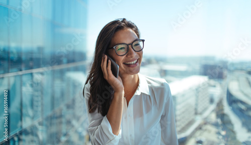 Canvas-taulu Smiling woman entrepreneur talking over phone.