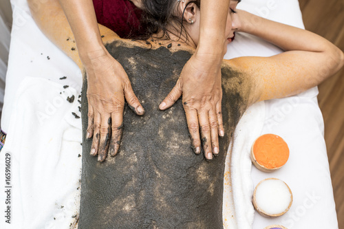 Beautiful Young Woman getting a mud massage at spa salon, health and healing concept. photo