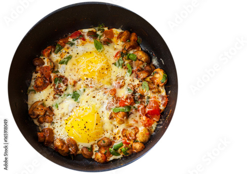 fried eggs with vegetables, mushrooms and cheese in a frying pan. top view. isolated on white