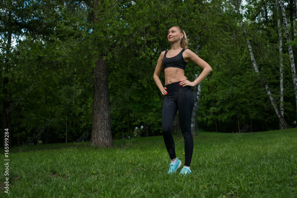 Beautiful girl in a park in black leggings and a top.