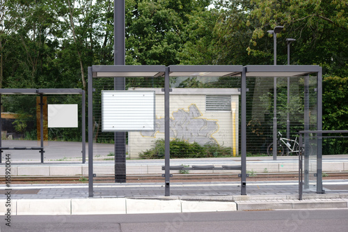 Straßenbahnhaltestelle / Der neue gebaute Glasunterstand einer Straßenbahnhaltestelle an einer Straße.