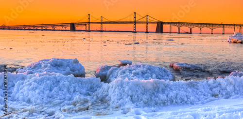 Photos sunrise by Chesapeake Bay Bridge in winter with icebergs and snow and ice on sho