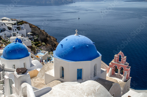 Oia Village  Santorini Cyclade islands  Greece. Beautiful view of a blue dome church and a pink tower-bell.
