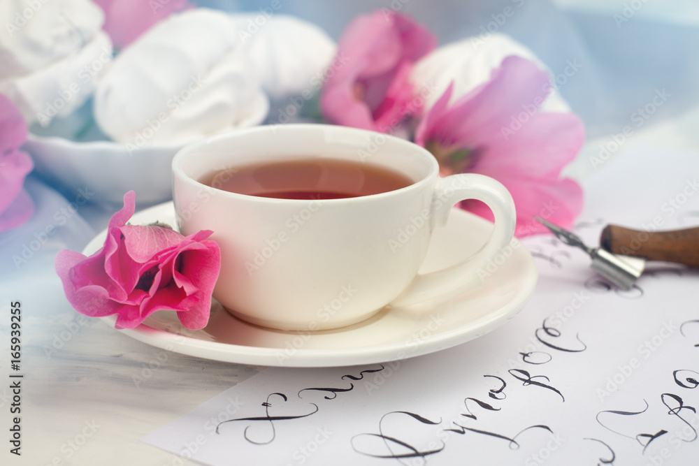 Composition with pink flowers, calligraphy tool, tea cup and zephyr cookies. Wedding, romantic lettering or springtime conception, toned photo