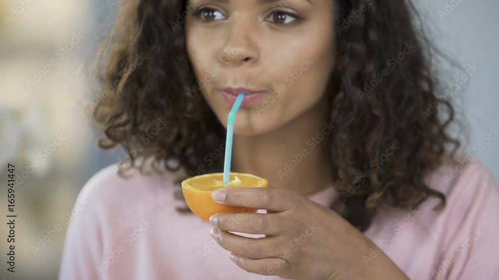 Young woman taking orange cut in half and drinking juice from it, lifestyle Young woman taking orange cut in half and drinking juice from it, lifestyle
