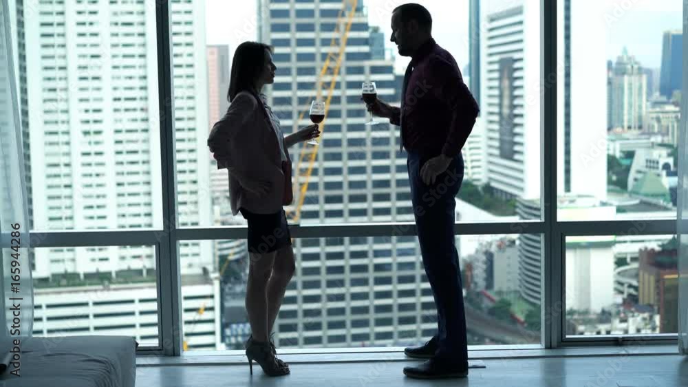 Businesspeople talking, drinking wine and admire view standing by window in office
Businesspeople talking, drinking wine and admire view standing by window in office