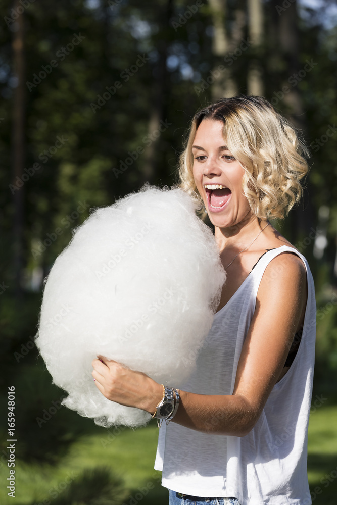 Girl eating sweet cotton candy in a summer park Girl eating sweet cotton candy in a summer park