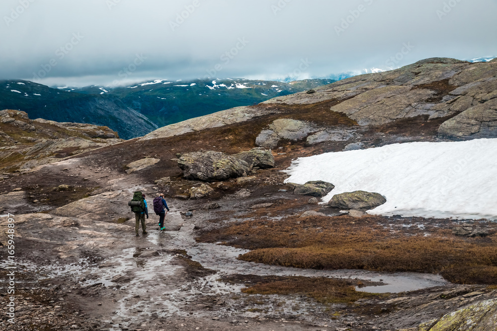 Tired happy people during beautiful Norway trip early morning in summer. Trolltunga hiking route. Norway