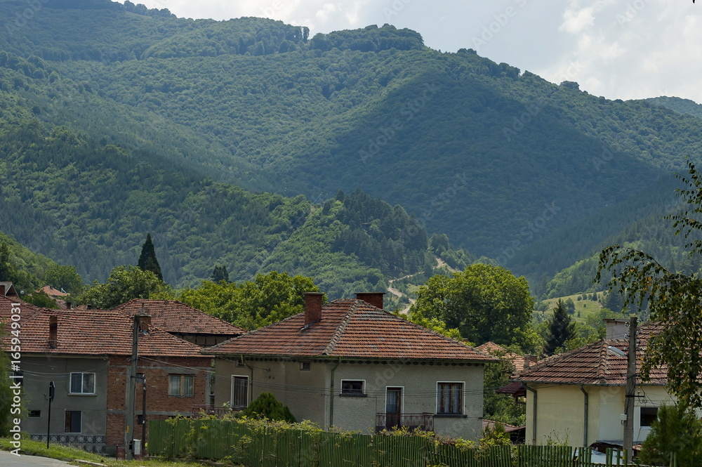 Scene with mountain glade, forest and residential district of bulgarian village Dushantsi, Central Balkan mountain, Stara Planina, Bulgaria