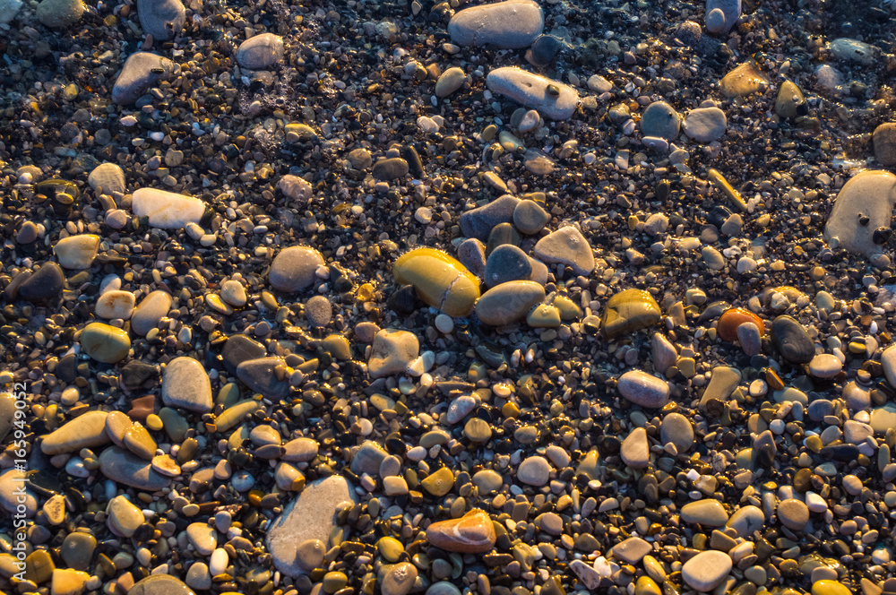 sea pebble beach with multicoloured stones, waves with foam