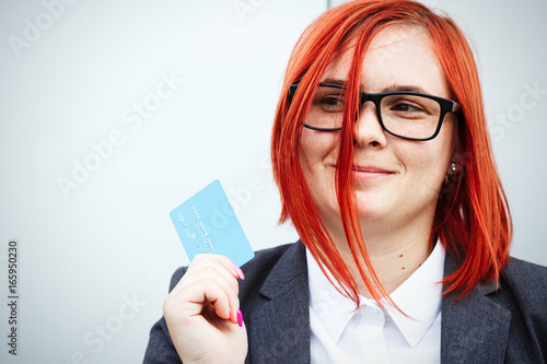 Concept of purchases, banking services. A woman in a suit and glasses shows a credit card. With a place for advertising text. photo