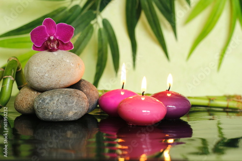 galets disposés en mode de vie zen sur la gauche avec une orchidée au sommet et une bougie rose allumées