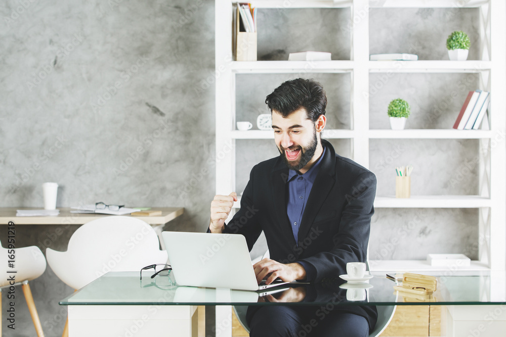 Naklejka premium Happy businessman using laptop at workplace